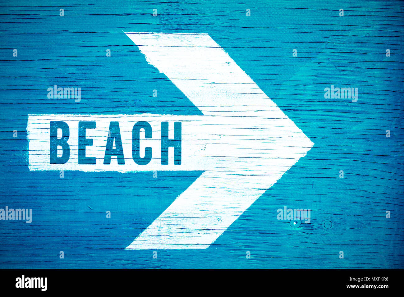 Strand text Zeichen auf einem weißen Pfeil, dessen Spitze nach rechts manuell auf einem blauen Schild aus Holz bemalt geschrieben. Konzept für heiße Sommer, tropi Stockfoto