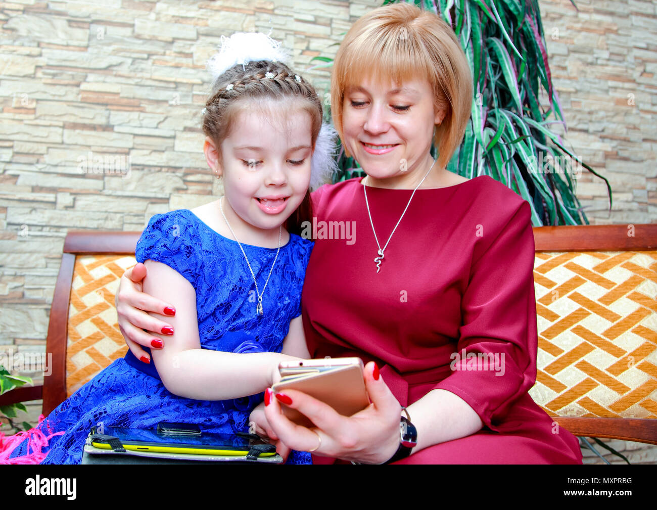 Glücklich liebende Familie. mom Umarmungen Tochter, die etwas an die Mama Telefon bedenkt. Stockfoto