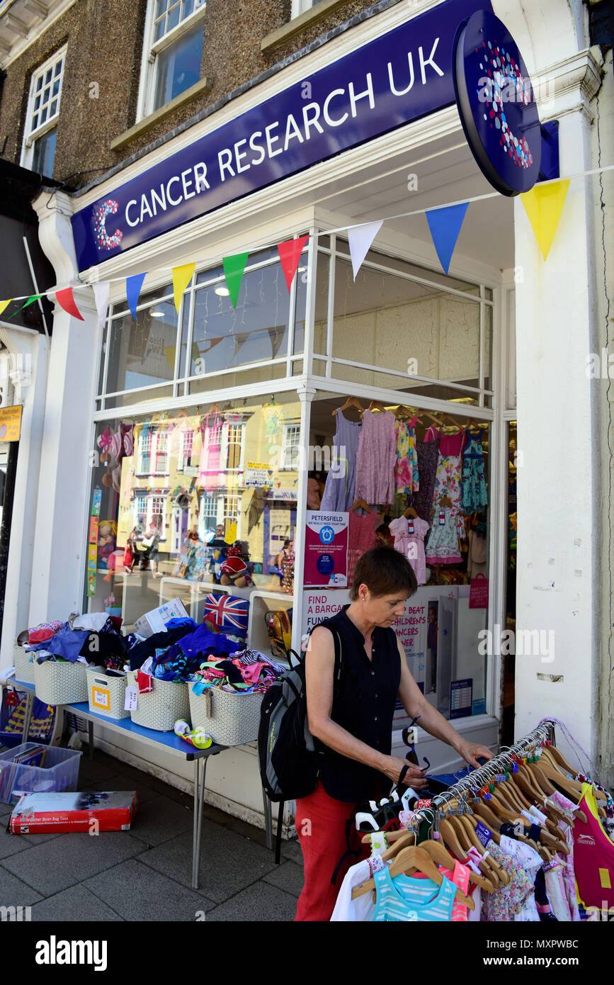 Frau durchsuchen gebrauchte Kleidung Abschnitt von Cancer Research UK Charity Shop, Petersfield, Hampshire, UK. Stockfoto