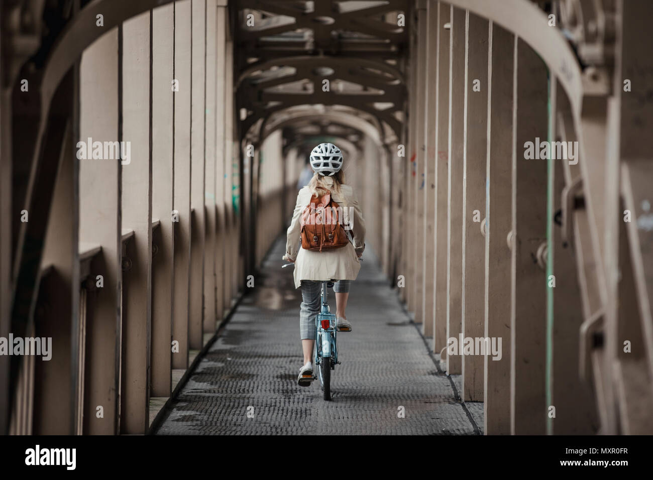 Rückansicht, weitwinkelstellung Eine nicht erkennbare Person das Radfahren über eine Brücke zu arbeiten. Stockfoto