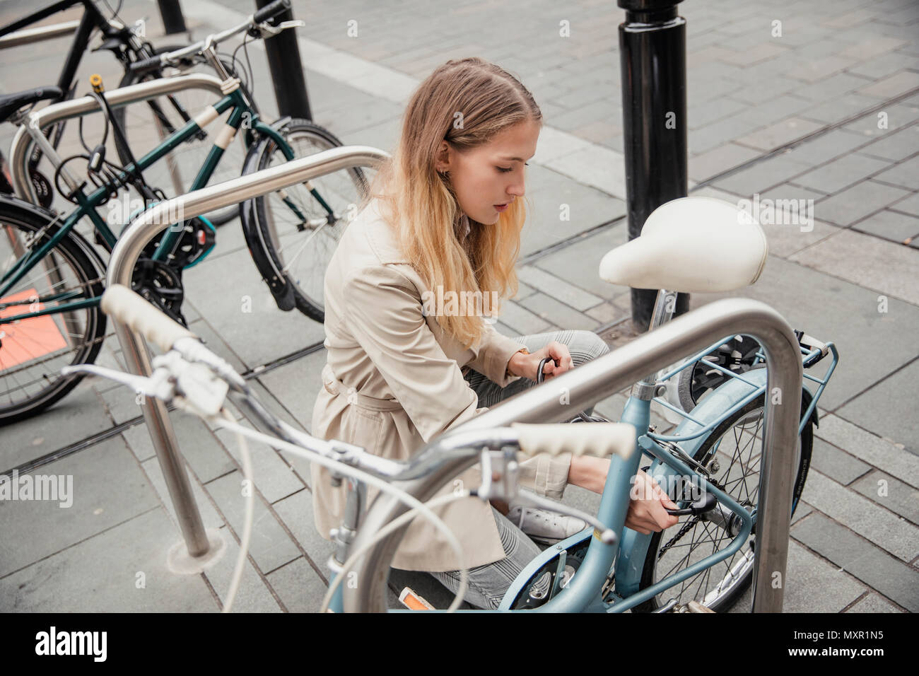 Junge Geschäftsfrau zu sperren ihr Fahrrad im Rack, bevor sie in Arbeit geht. Stockfoto