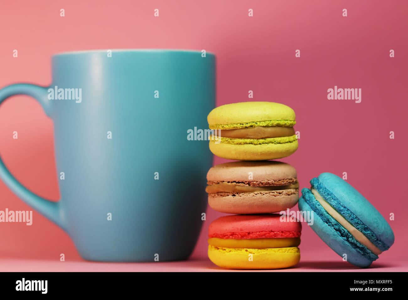 Blaue Tasse Tee auf rosa Hintergrund mit makronen Stockfoto