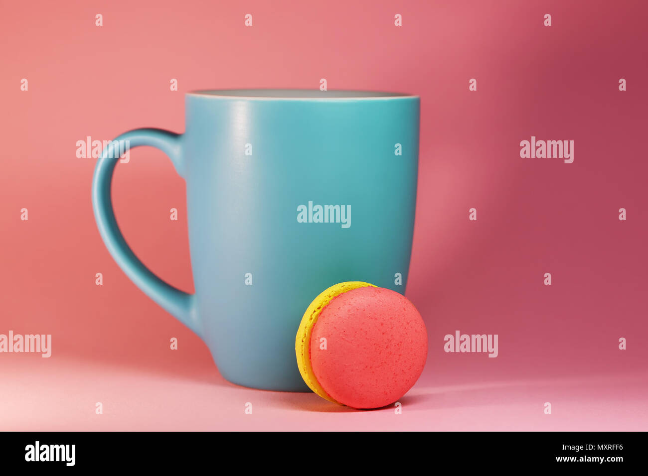 Blaue Tasse Tee auf rosa Hintergrund mit makronen Stockfoto