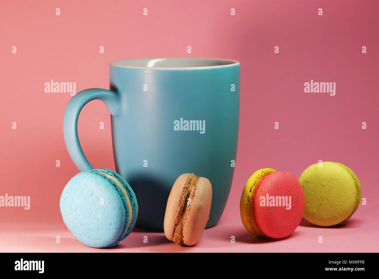 Blaue Tasse Tee auf rosa Hintergrund mit makronen Stockfoto