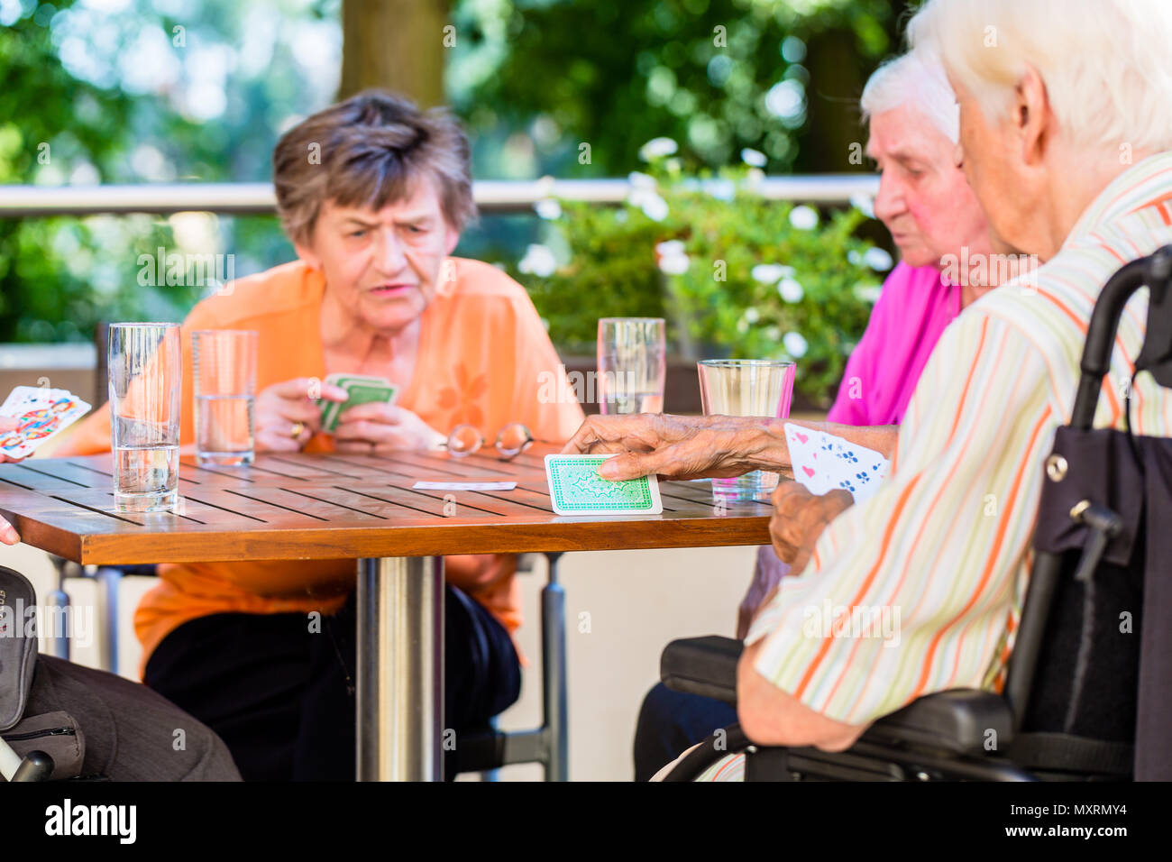 Gruppe von Senioren spielen Brettspiel auf der Terrasse des Seniorenheims Stockfoto