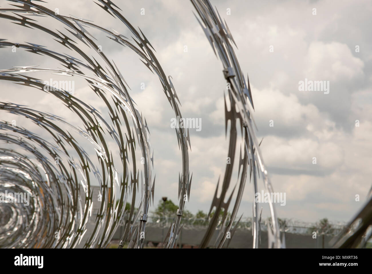 Nahaufnahme von gerollter Stacheldraht auf Metall Zaun an verlassenen Gefängnis Hof. Stockfoto