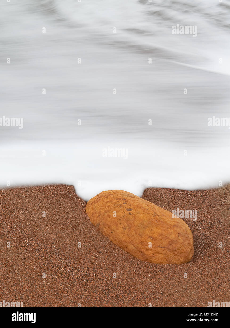 Sandsteinfelsen am Sandstrand mit Seidigen milchigen Schaum Wellen durch die Verschlusszeit zu verlangsamen. Sandwick Bay, Whitby, North Yorkshire Stockfoto