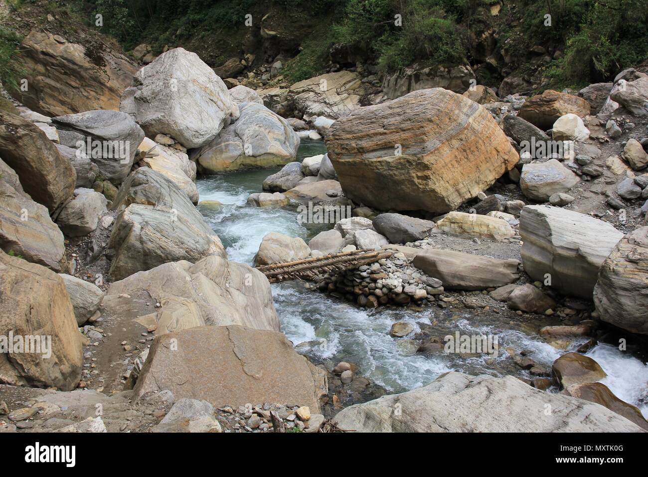 Kimrong Khola, Fluss in der Nähe von Ghandruk, Nepal. Holzbrücke und Big Boulder. Stockfoto