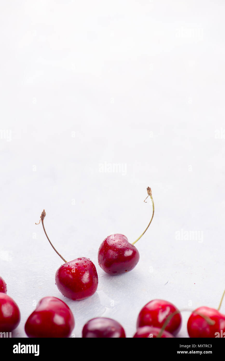 Zwei süße Kirschen mit Wassertropfen auf einem weißen Hintergrund. Makro Beeren shot mit Kopie Raum Stockfoto