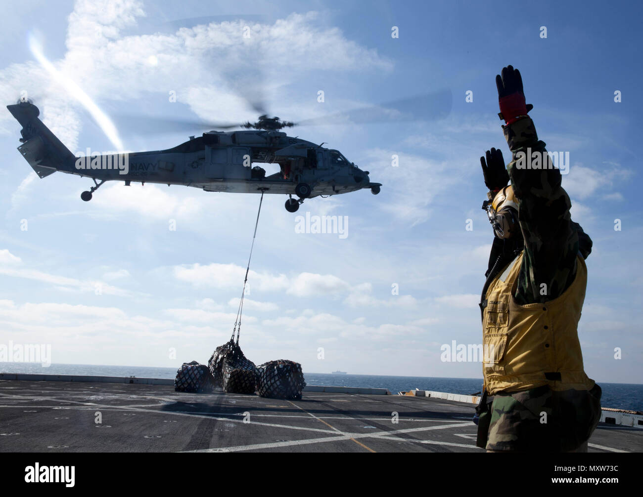 Chief Petty Officer Eugene Williams, eine Landung einweisende mit der USS Mesa Verde LPD (19), führt eine MH-60S Seahawk Helikopter liefern cargo Paletten auf dem Flugdeck der USS Big Horn (T-AO 198) Mutterschiff auf Dez. 8, 2016 während einer vertikalen Nachschub während der Amphibischen bereit Gruppe Marine Expeditionary Unit Übung Dez. 8, 2016, als die USS Bataan über den Horizont. Während der dreiwöchigen Ausbildung evolution, Marines wird eine breite Palette von Maßnahmen und Szenarien die Verbesserung der Interoperabilität und amphibische Kriegsführung Fähigkeiten mit ihren Marine Pendants bekämpfen. Verstärkung bei s Stockfoto