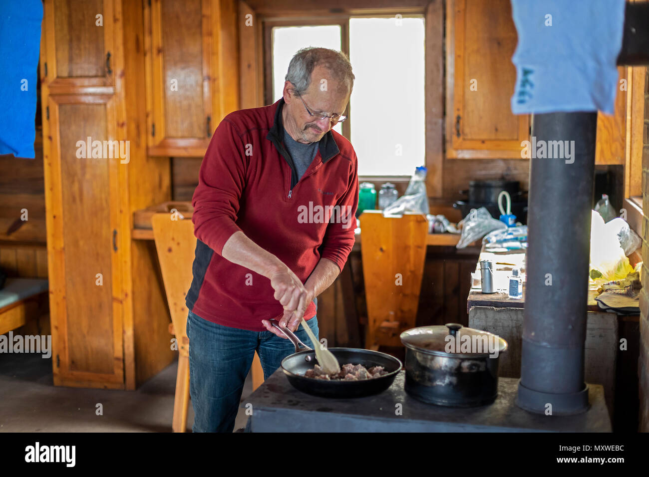 Ontonagon, Michigan - John West kocht das Abendessen auf einem Holzofen in einem Backpackers' Kabine in Porcupine Mountains Wilderness State Park. Der Park unterhält Stockfoto