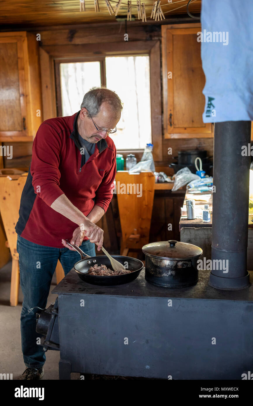 Ontonagon, Michigan - John West kocht das Abendessen auf einem Holzofen in einem Backpackers' Kabine in Porcupine Mountains Wilderness State Park. Der Park unterhält Stockfoto