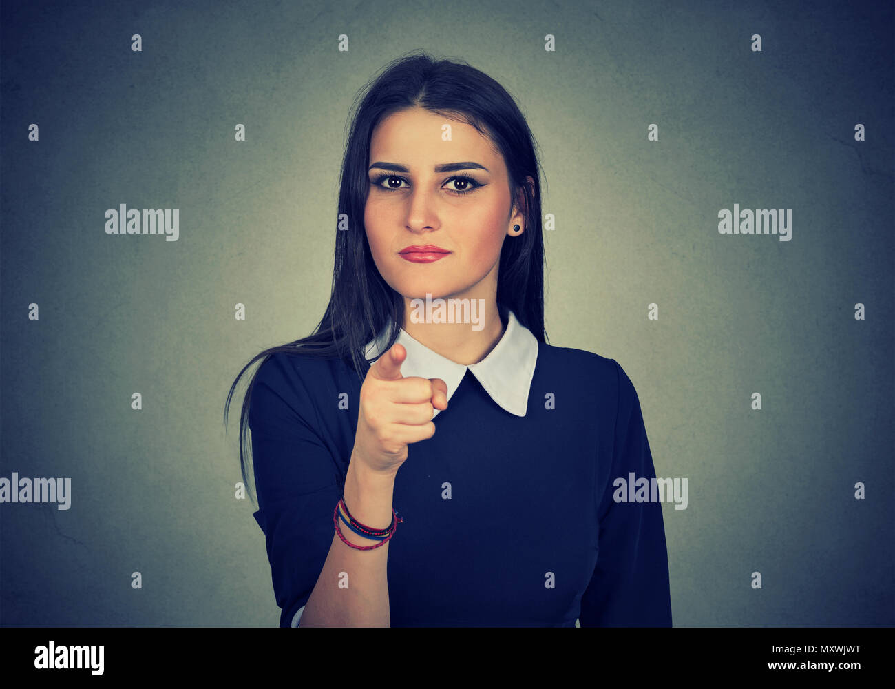 Junge zuversichtlich brunette, Auswahl und zeigen auf Kamera in Anzeige auf grauem Hintergrund Stockfoto