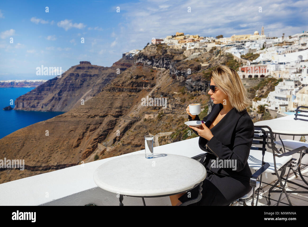 Junge Frau trinkt Kaffee in einem Restaurant in Santorini, Griechenland. Stockfoto