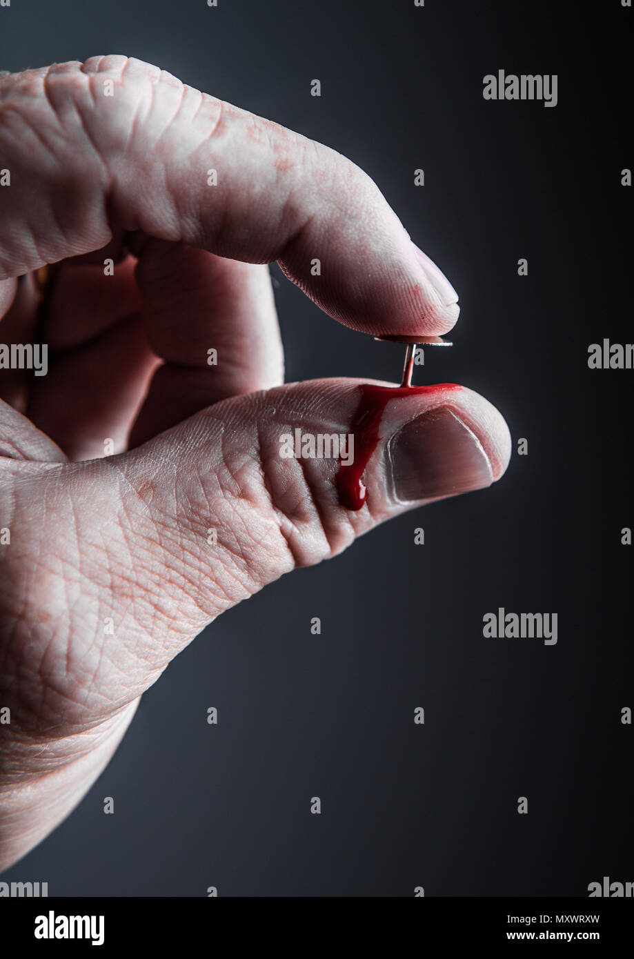 Ein Mann die Hand einen Reißnagel in seinen Daumen Stockfoto