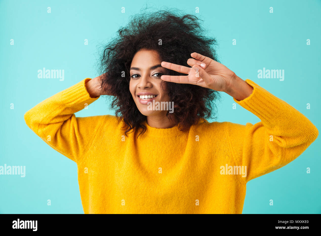 Bunte Porträt der erstaunliche Frau mit zotteligen Haaren lächelnd und mit Sieg Symbol mit dem Finger über blauen Hintergrund isoliert Stockfoto