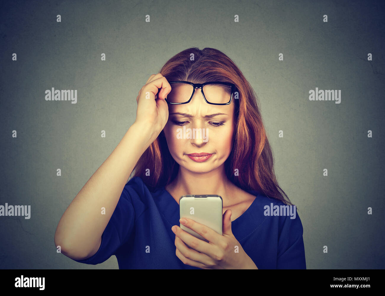 Junge rothaarige Mädchen, dass Brillen und beobachten Smartphone Probleme mit Augen Stockfoto