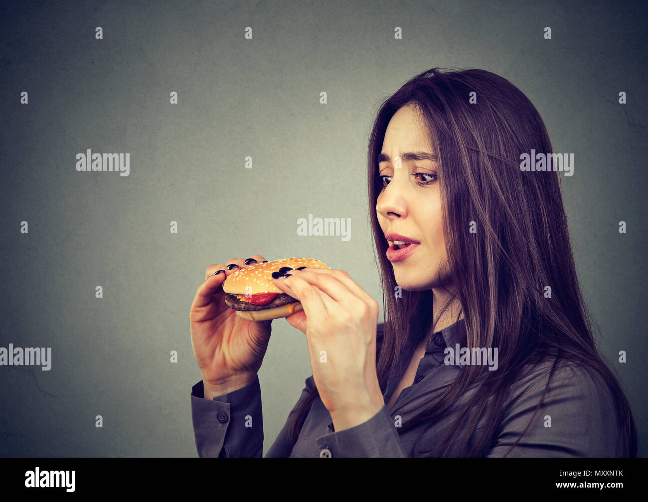 Pretty girl Holding köstlichen Cheeseburger und suchen ganz mit dem Wunsch, es zu essen besessen Stockfoto