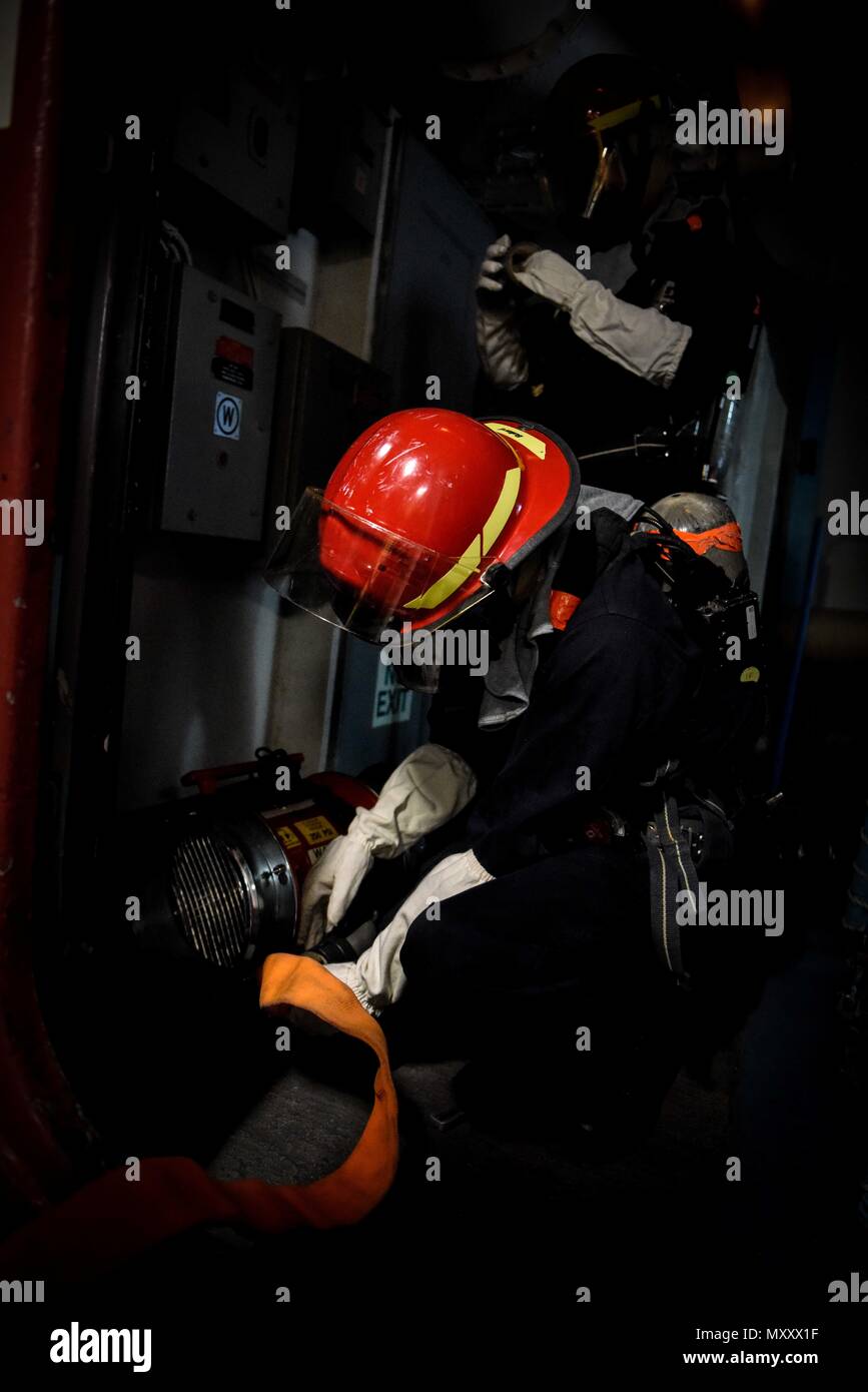 161212-N-MB 932-433 SAN DIEGO (31. 12, 2016) Petty Officer 2nd class Christian Logan verbindet einen Schlauch zu einem de-Rauchen Wassereinlass in einem dunklen Raum während ein Schiff - große Übung (Damage Control Rodeo), in denen Segler aus verschiedenen Stationen drehen basic Schiff Qualifikationen zu erlernen, an Bord der Flugzeugträger USS Theodore Roosevelt (CVN 71). Theodore Roosevelt ist derzeit günstig und homeported in San Diego, die sich eine geplante geplante Wartung Verfügbarkeit. (U.S. Marine Foto von Petty Officer 3. Klasse Jimmi Lee Bruner/Freigegeben) Stockfoto