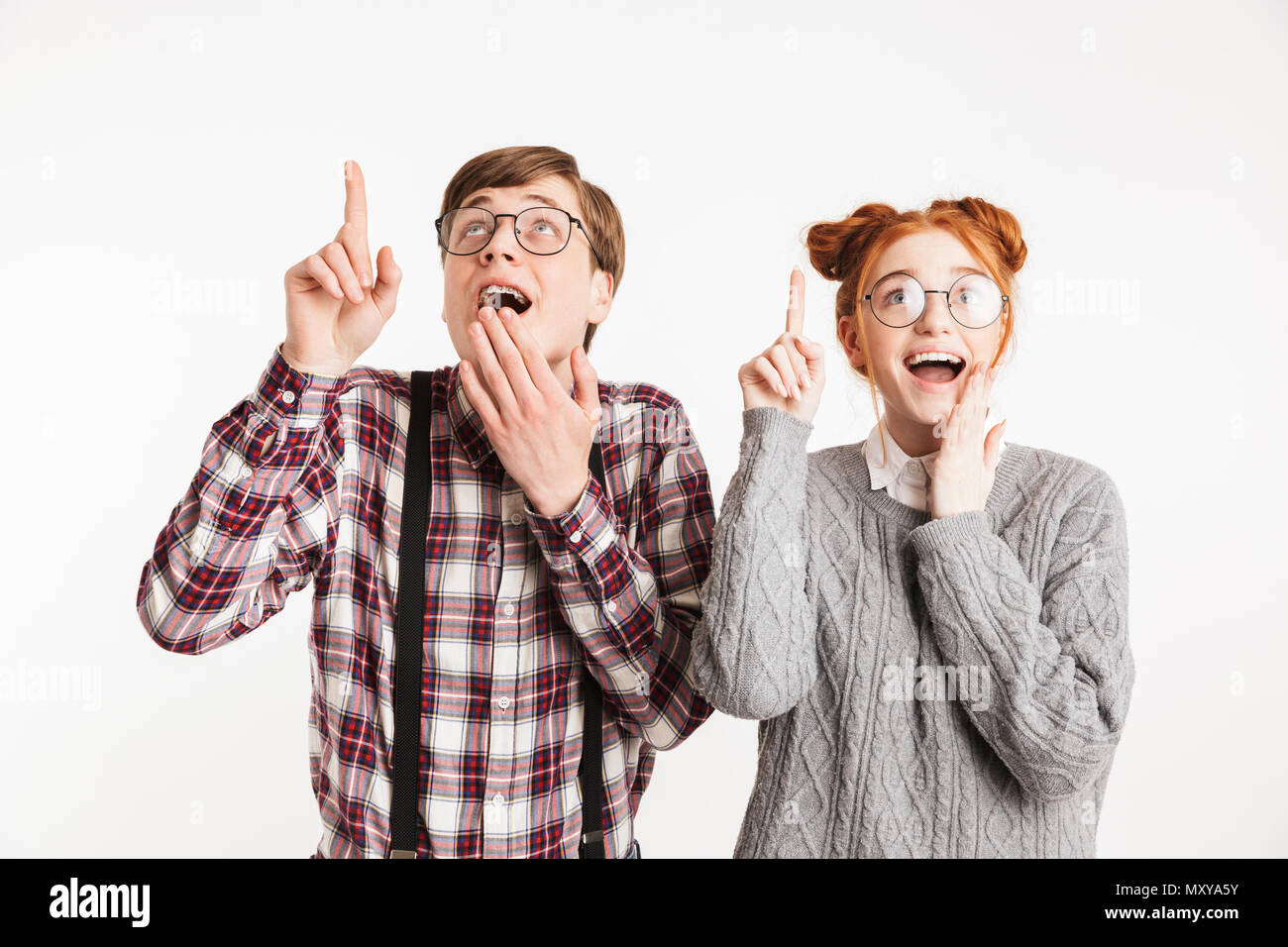 Glückliches Paar der Schule nerds Pointing Finger bei copy Space auf weißem Hintergrund Stockfoto