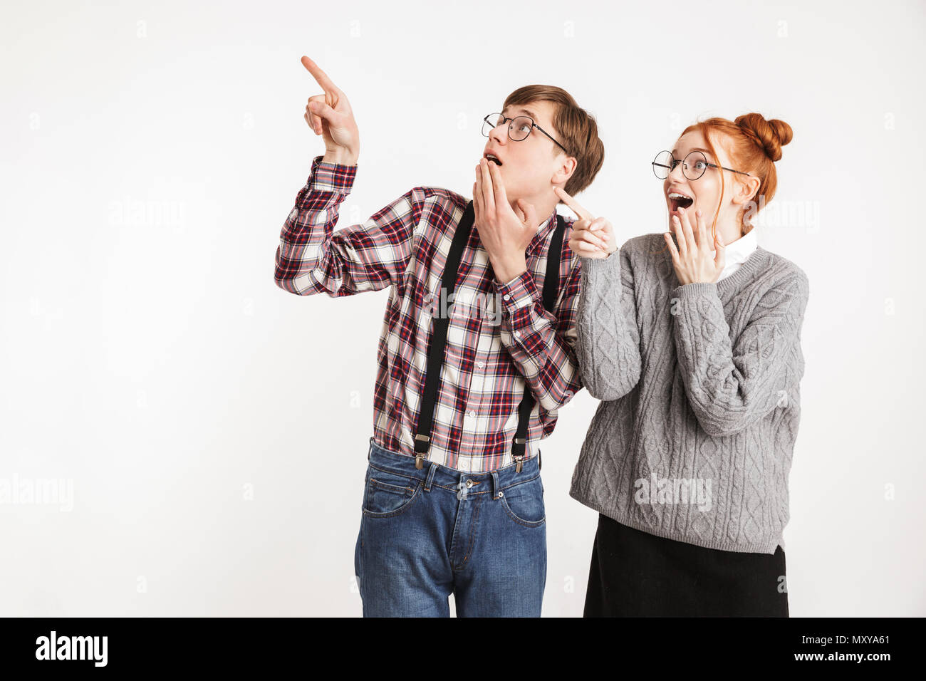 Freundliche paar Schule nerds Pointing Finger weg bei copy Space auf weißem Hintergrund Stockfoto