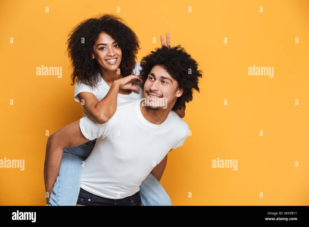 Portrait Of Happy afrikanischen Mann, Freundin auf seinem Rücken über Gelb Hintergrund isoliert Stockfoto
