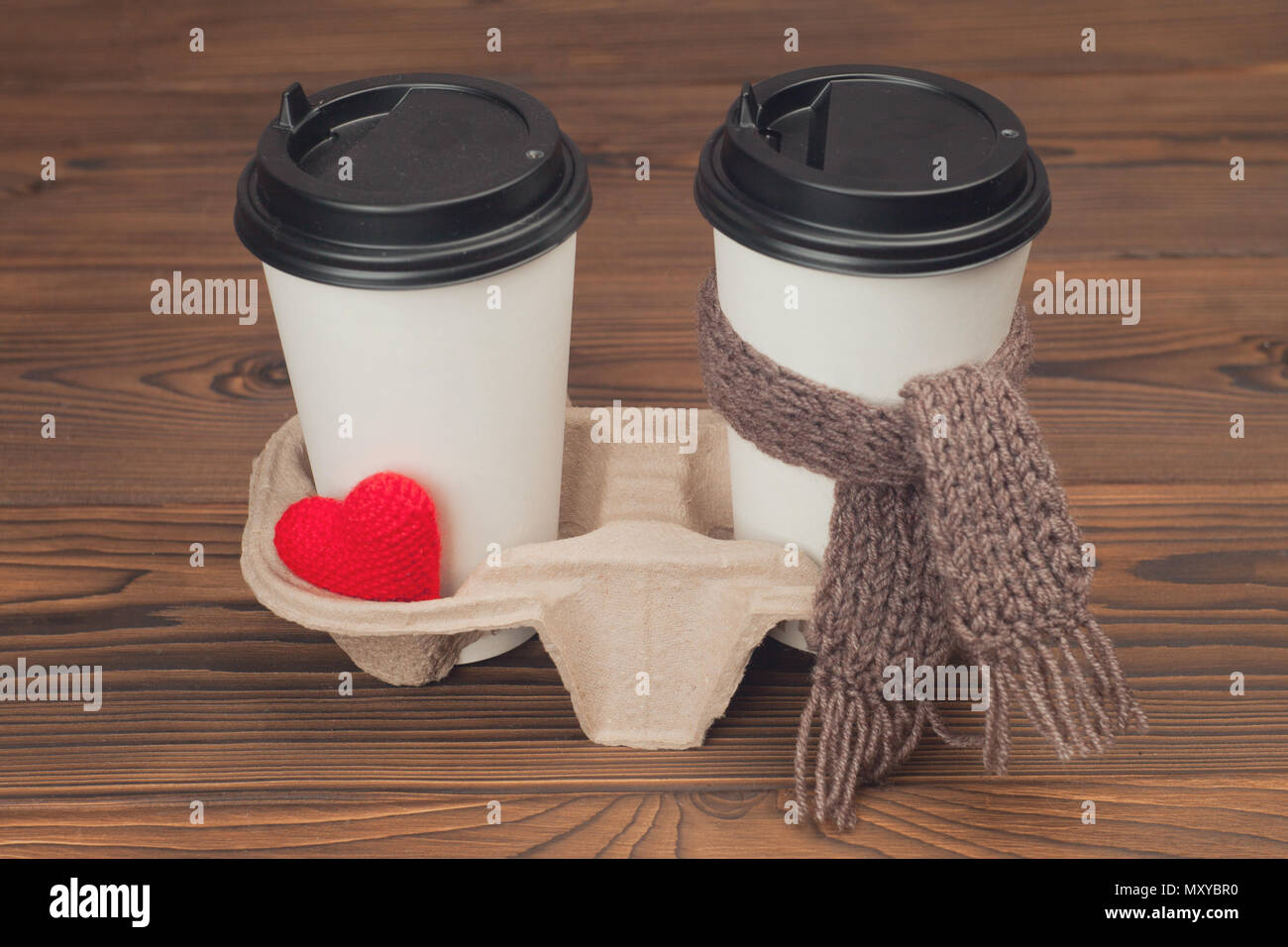 Zwei Tassen Kaffee mit Stricken sie Herz und Schal auf Holz- Hintergrund Stockfoto