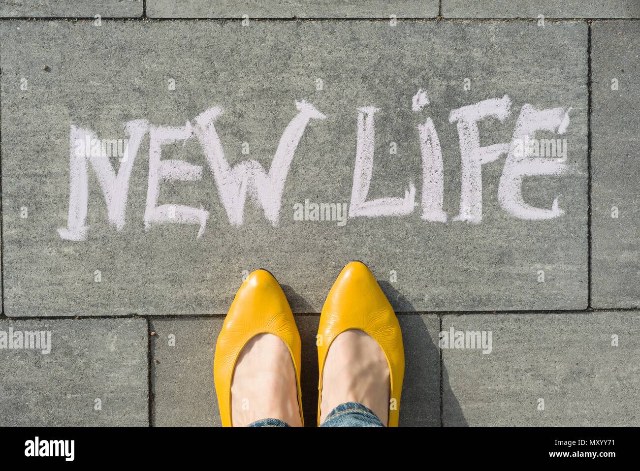 Weibliche Füße mit Text neues Leben auf Asphalt geschrieben. Stockfoto