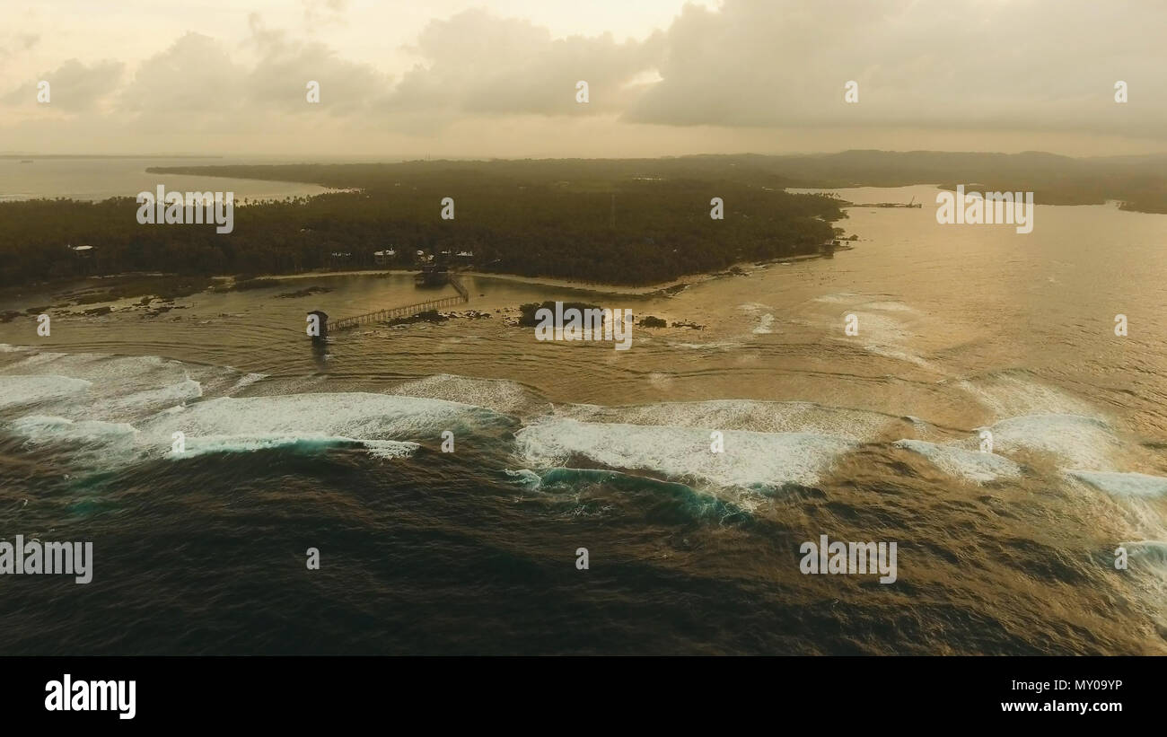 Aussichtspunkt im Meer an Cloud Nine Surf Point bei Sonnenuntergang, Siargao Island, Philippinen. Luftaufnahme angehoben Holzsteg für Surfer das Riff von Siargao Island auf Wolke 9 surf Pause Mindanao. Siargao Inseln berühmte Brandung zerschlagen Wolke 9. Fliegen über dem blauen Meer im azurblauen Lagune. Stockfoto