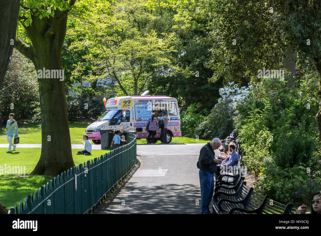 Ein Eis van verkaufen Eis in einem öffentlichen Park an einem warmen sonnigen Tag in Großbritannien. Die Menschen genießen die Sonne und das warme Wetter in Botanischen Gärten, Belfas Stockfoto