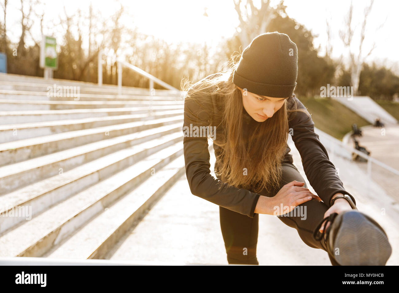 Bild von Behinderten gesundes Mädchen in Sportkleidung Training und Stretching Beinprothese auf Geländer in Stadion außerhalb Stockfoto