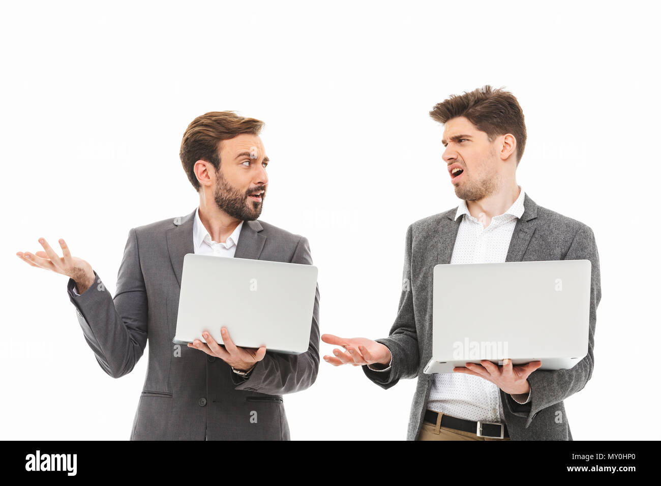 Porträt einer zwei verwirrte Geschäftsleute mit Laptops und Sprechen auf weißem Hintergrund Stockfoto