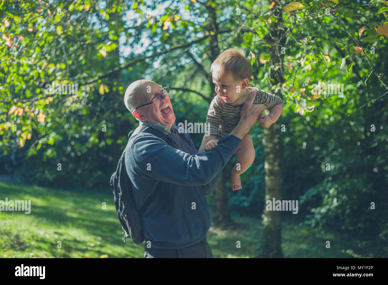 Ein älterer Mann hebt von seinem Enkel in der freien Natur Stockfoto