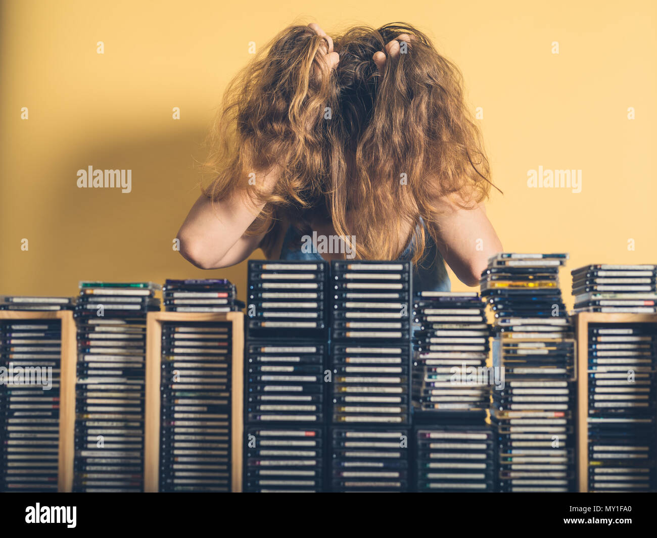 Eine junge Frau ist frustriert sammelte sie Stapel von veraltet und nutzlos minidiscs Stockfoto