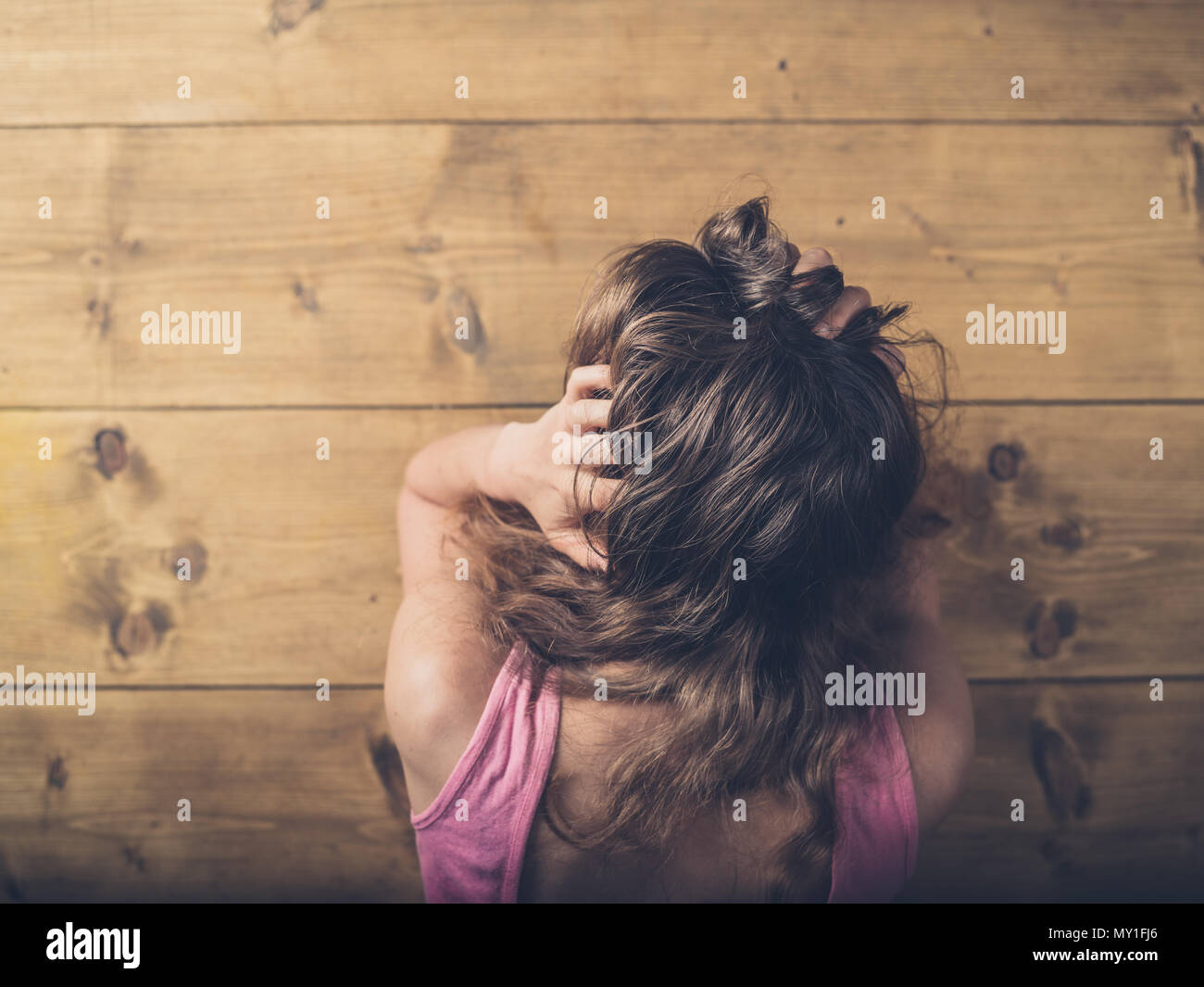Eine traurige und verärgert Frau sitzt an einem Tisch und ihr Haar ziehen Stockfoto