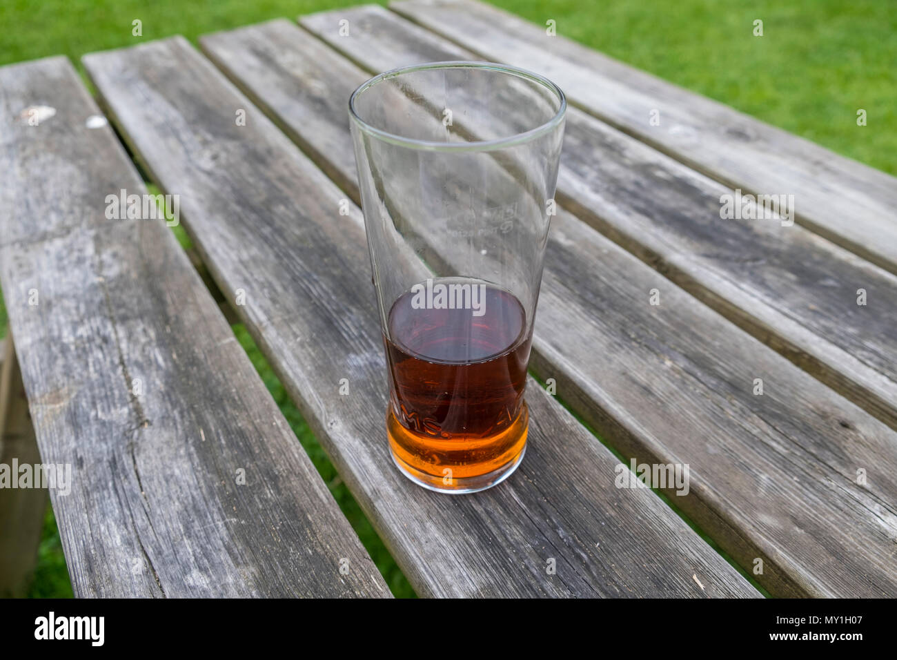 Halb voll Pint Adnams bitter auf einem pub Tabelle. Übersicht Glas halb voll oder halb leer ist. Suffolk, Großbritannien. Stockfoto