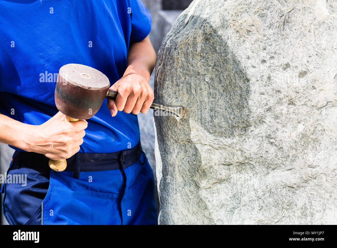 Steinmetz arbeiten auf Boulder mit sledgehammer und Bügeleisen Stockfoto