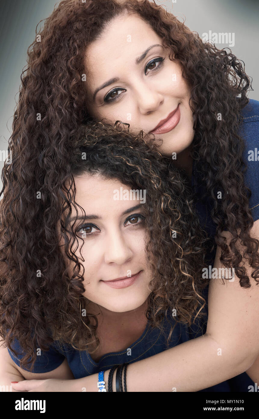 Brasilianische Musiker Zwillingsschwestern Silvana und Rosana mit ihren wilden lockigen Haaren umarmen posiert vor der Kamera, Nahaufnahme Porträt Stockfoto