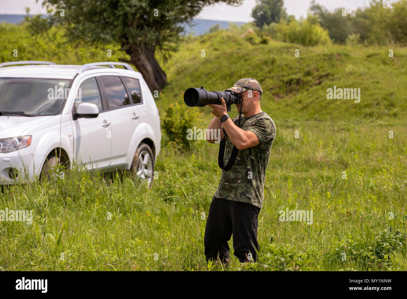 A Bird Watcher und Vogel Fotograf mit einem großen Teleobjektiv, in einem Feld Stockfoto