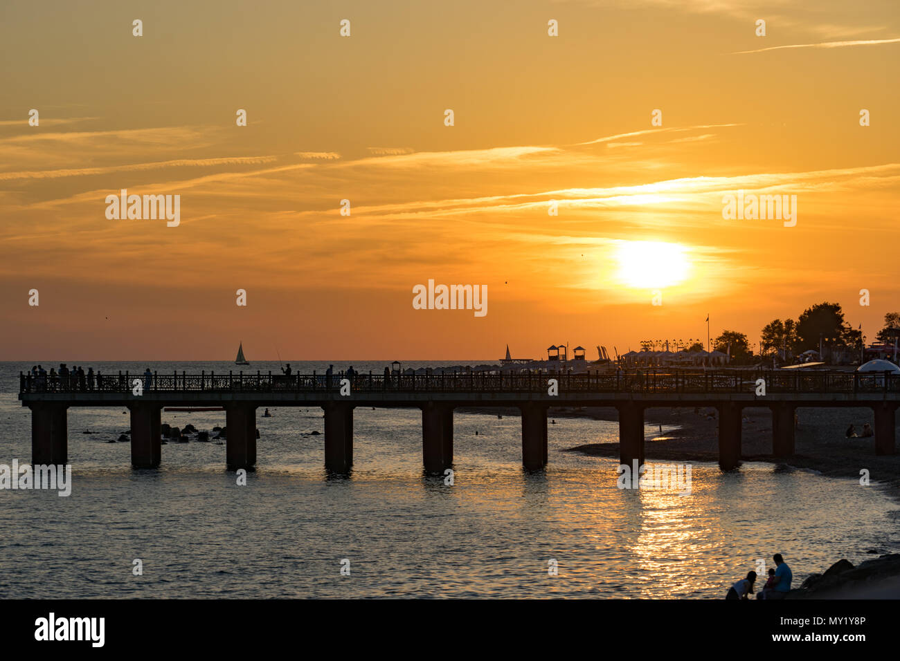 Farbenfroher Sonnenuntergang über Imeretinskaya Damm von Sotschi und Silhouette der Pier. Stockfoto