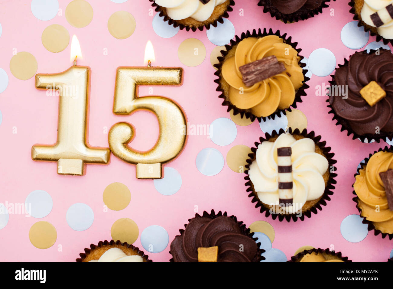Nummer 15 gold Kerze mit Cupcakes gegen ein Pastell rosa Hintergrund Stockfoto