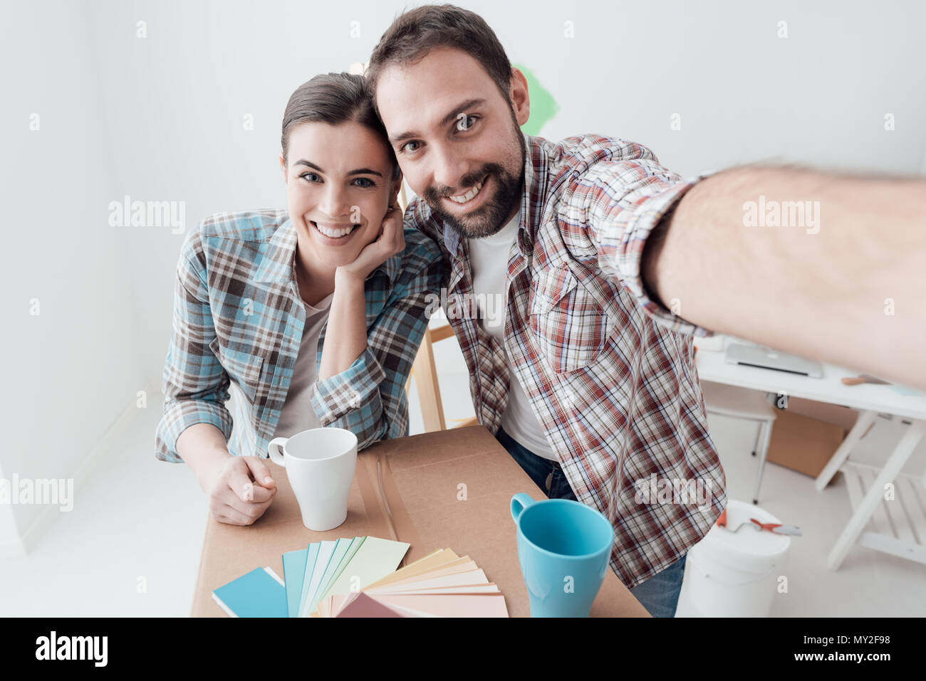 Lächelnd junges Paar Einzug in ihr neues Haus und eine Haus Makeover zu tun, nehmen sie ein Selbstporträt Stockfoto