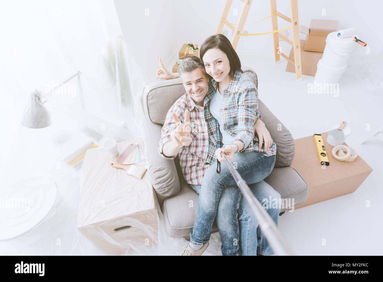 Glückliches Paar unter selfies zu Hause, während sie Haupterneuerungen, Sie sitzen auf einem Sessel und lächelnd Stockfoto