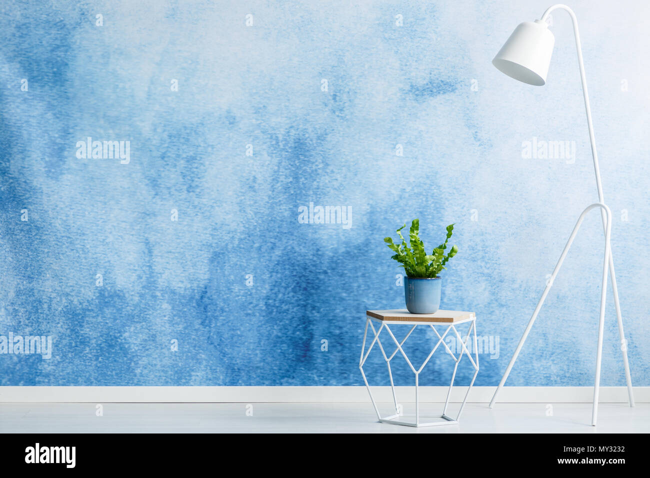 Leere wand für die Produktplatzierung, Hocker mit einer Pflanze und weiße Lampe im Wohnzimmer Innenraum Stockfoto