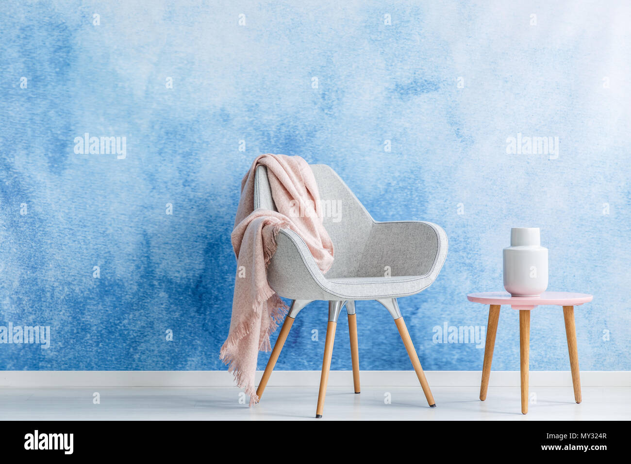 Wohnzimmer mit einer Decke auf einen Sessel und Couchtisch, eine weiße Vase auf einem ombre Wand gesetzt. Ihr Produkt Stockfoto
