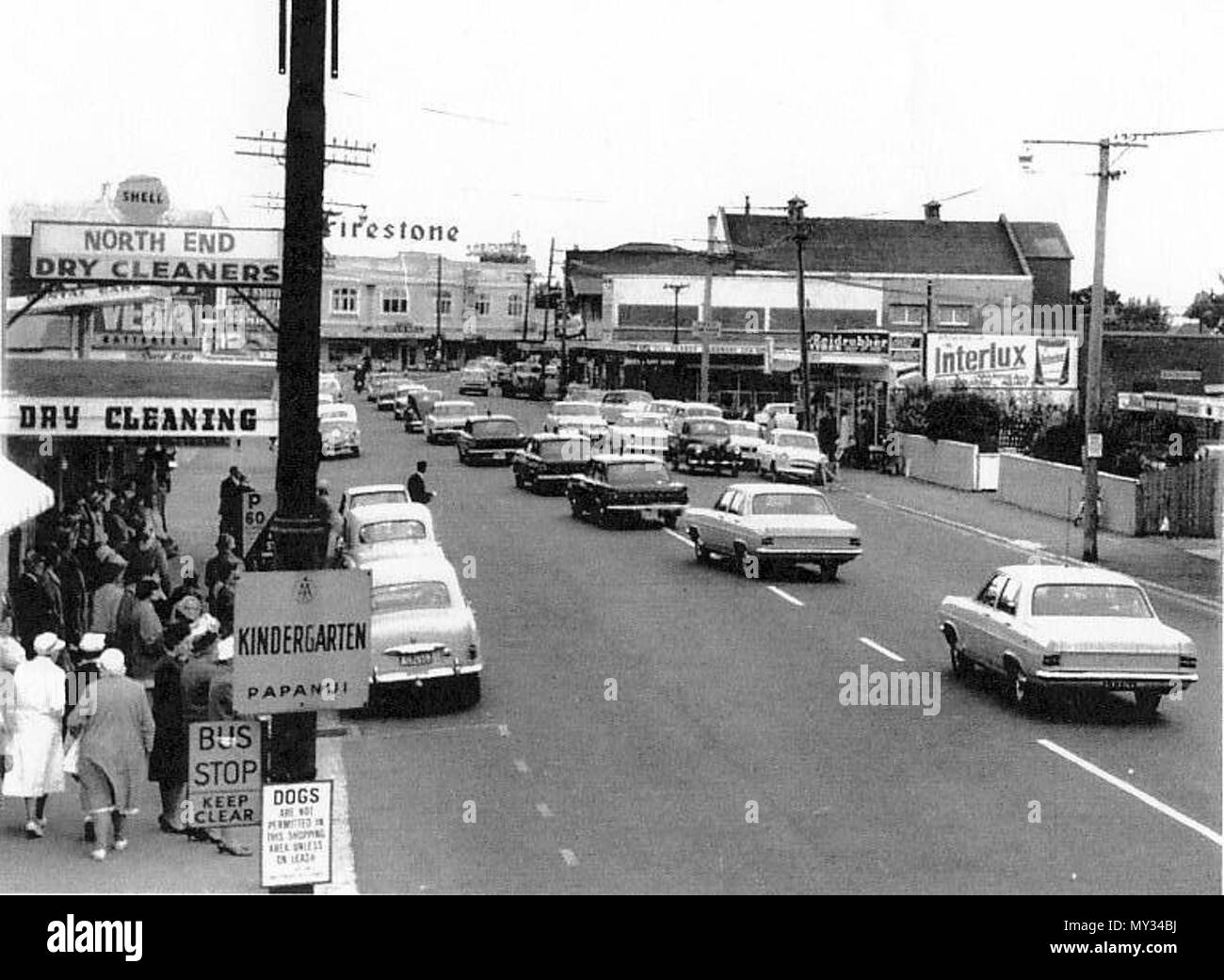 . Englisch: Konvoi. Auf der Suche nach Papanui Kreuzung Kreisverkehr mit Fahrzeugen, die auf der Parade mit mehreren (mindestens 5) Polizei Autos. ca. 1967. 1966 oder 1967. Stan McKay 407 Papanui 1966 Stockfoto