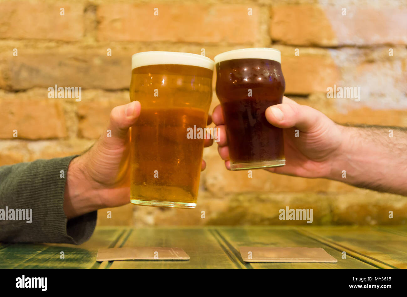 Freunde an der Bar Tisch halten zwei Pints Bier, Prost Stockfoto