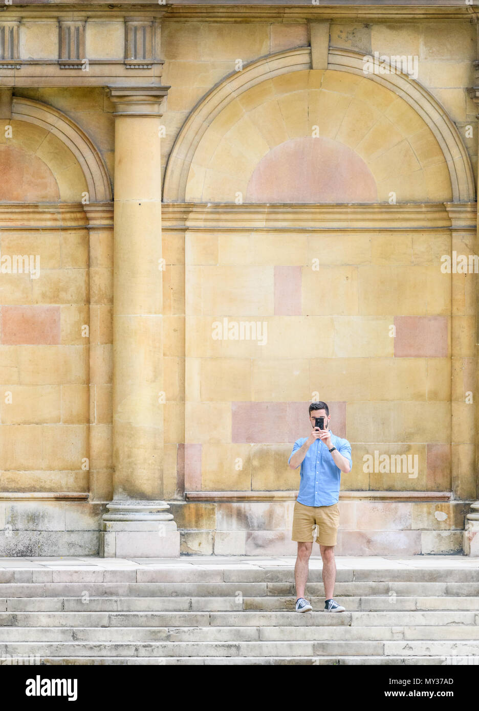 Student steht und nimmt ein Foto mit der Kamera auf die Schritte, die außerhalb des Ess Rooom am Trinity College der Universität Cambridge, Engla Stockfoto
