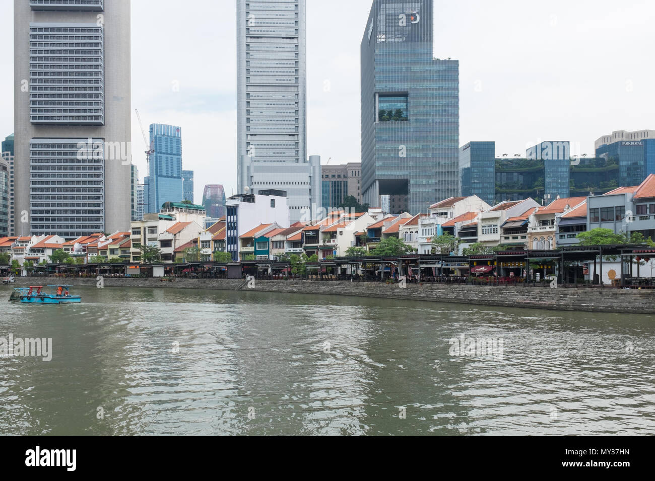 Bars und Restaurants säumen die Ufer des Singapore River am Boat Quay von hohen Bürogebäuden hinter Ihnen überschattet. Stockfoto