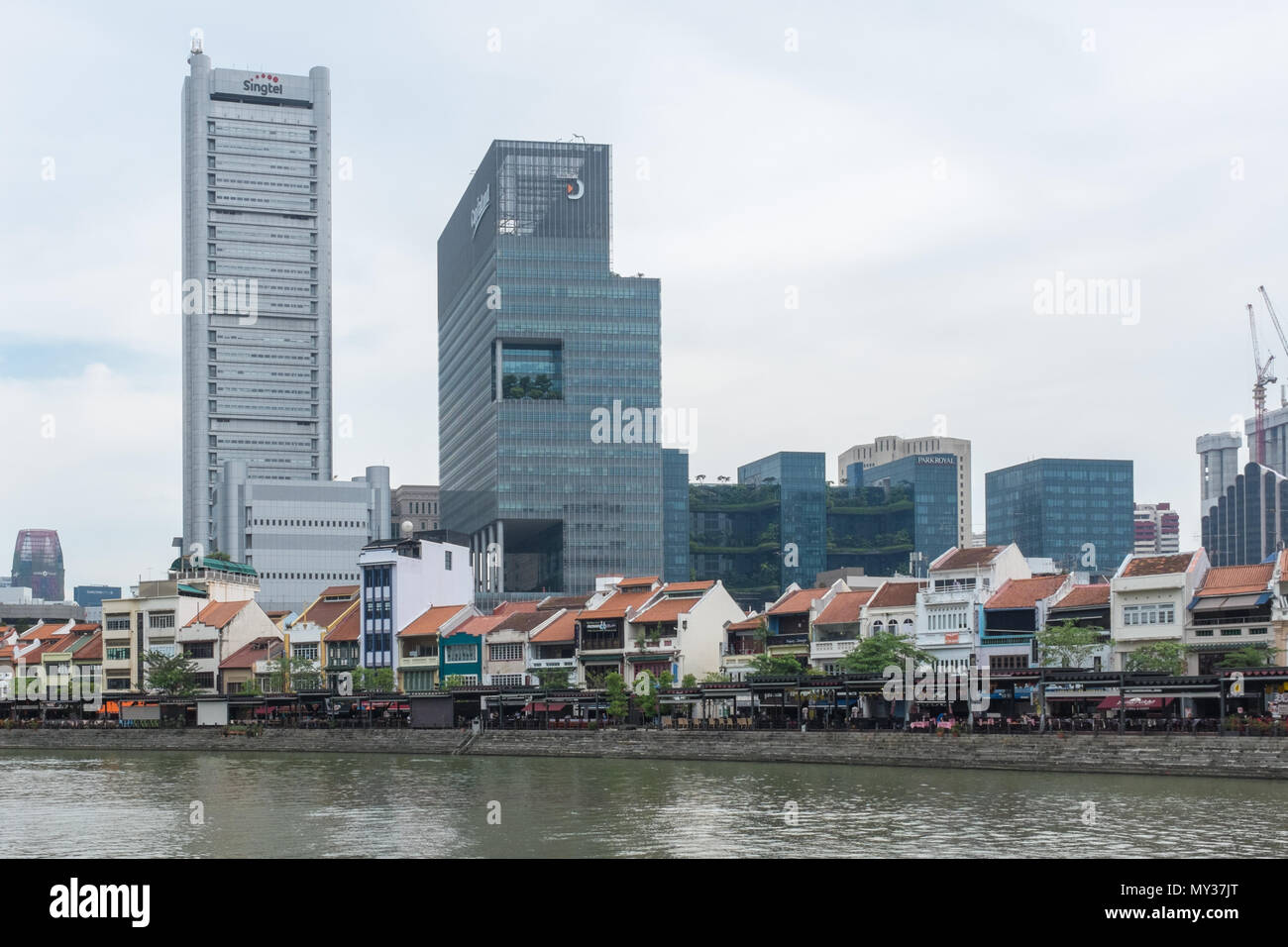 Bars und Restaurants säumen die Ufer des Singapore River am Boat Quay von hohen Bürogebäuden hinter Ihnen überschattet. Stockfoto